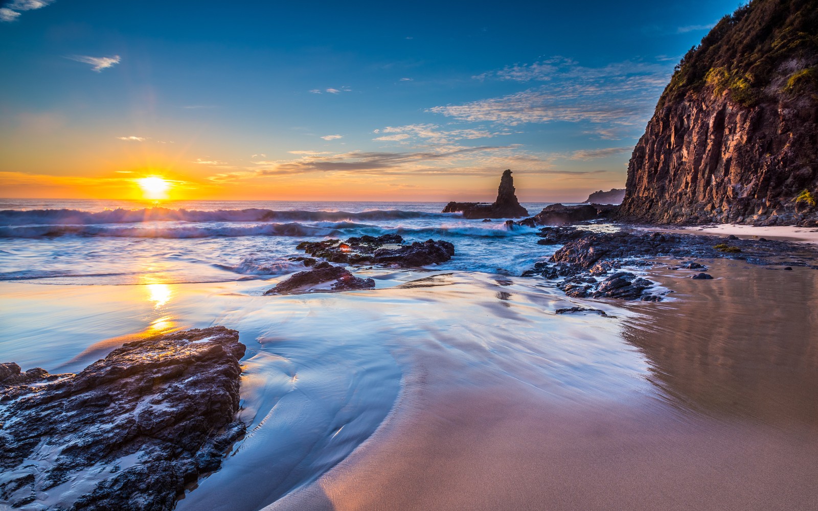 Une plage avec des rochers et de l'eau au coucher du soleil avec un phare au loin (jones beach, kiama downs, australie, lever de soleil, paysage marin)