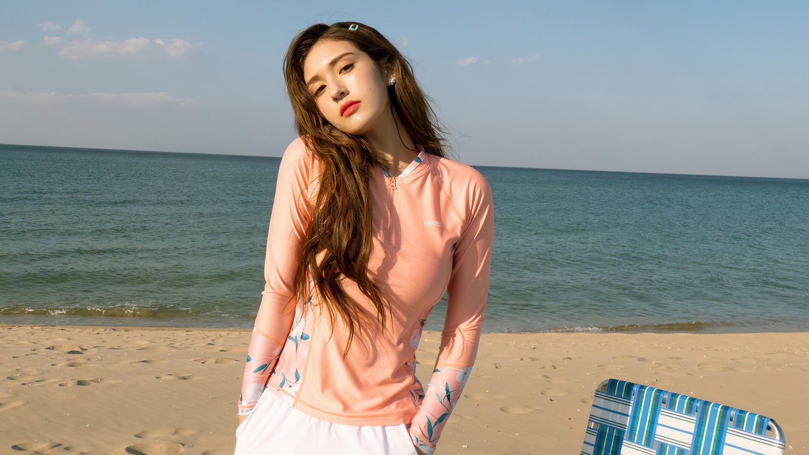 Una mujer de pie en una playa con una maleta frente a ella (somi, 소미, ennik somi douma, jeon somi, jeon so mi)