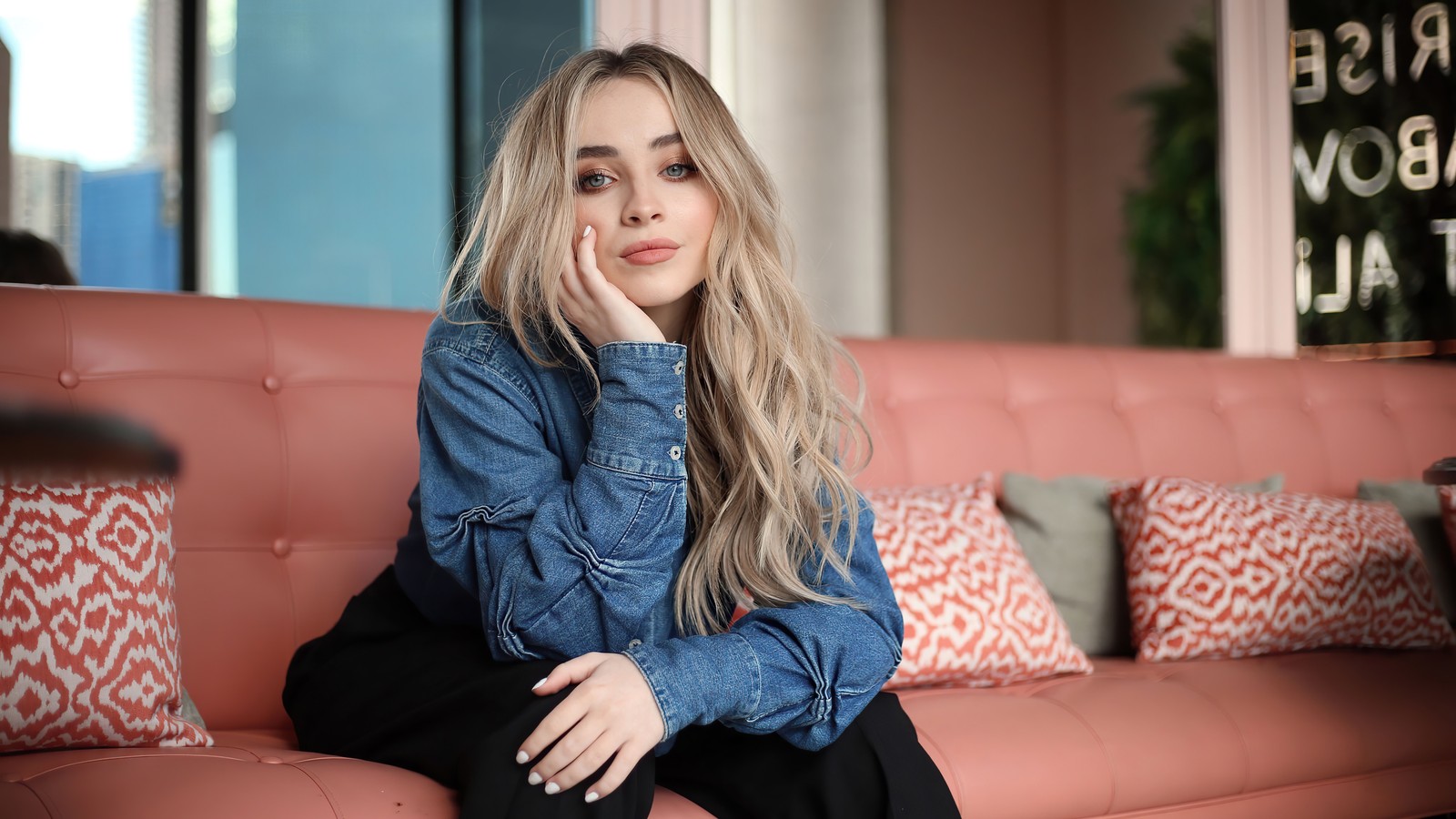 Mulher borrada sentada em um sofá rosa em uma sala de estar (sabrina carpenter, americano, cantor, celebridade, meninas)