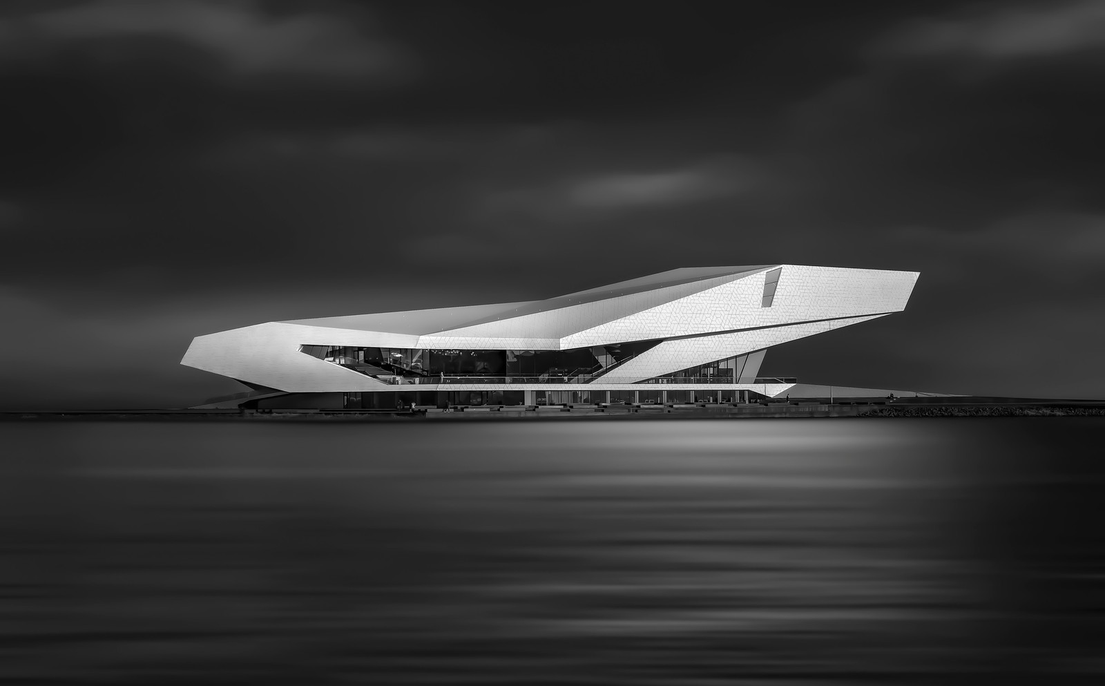 Una foto en blanco y negro de un edificio en la playa (cielo, arquitectura, avión, aerolínea, monocromo)