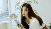 Saerom from fromis_9 reading a book in a bright, serene setting.