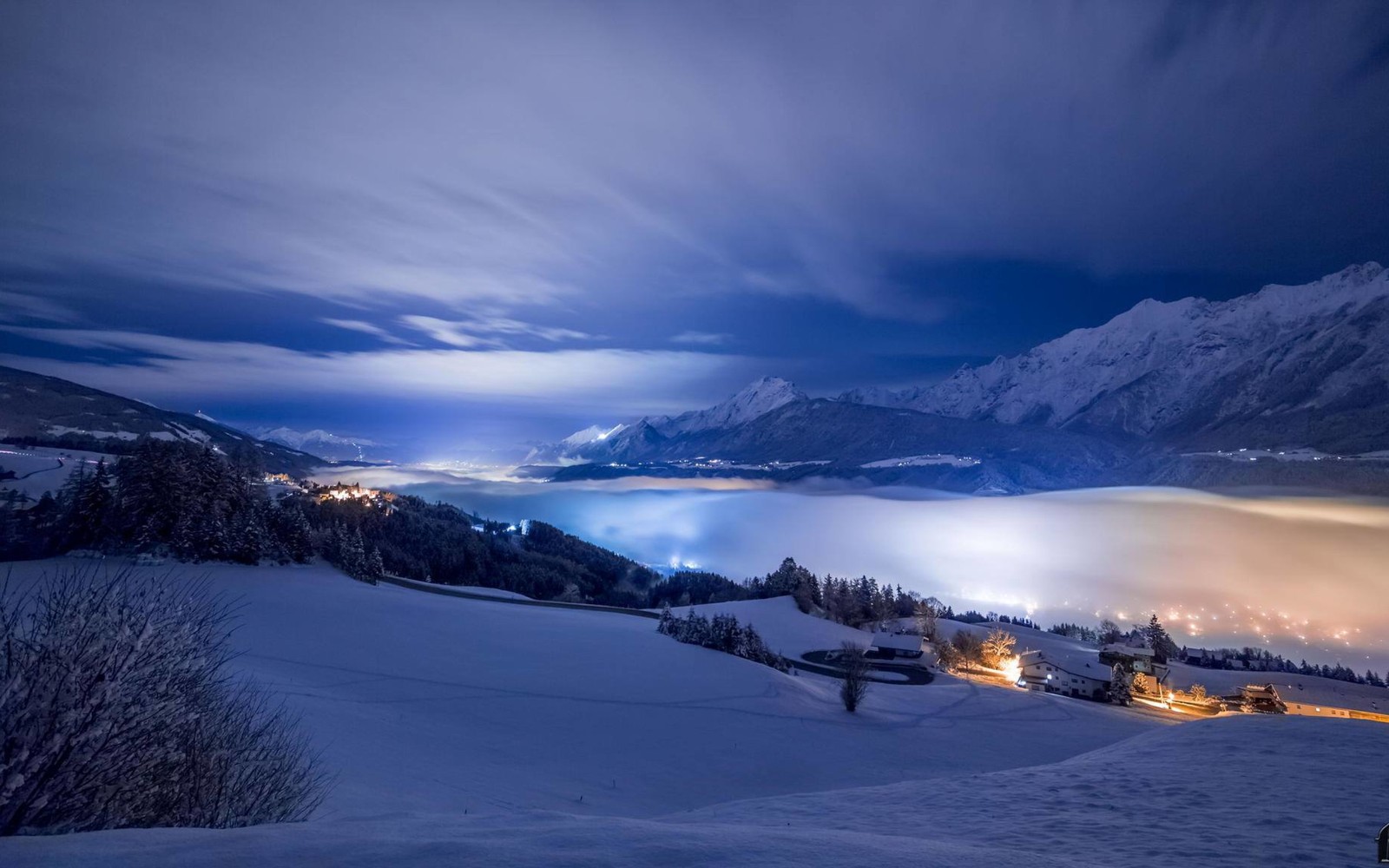 A view of a snowy mountain with a town below it (winter, snow, mountain, cloud, freezing)