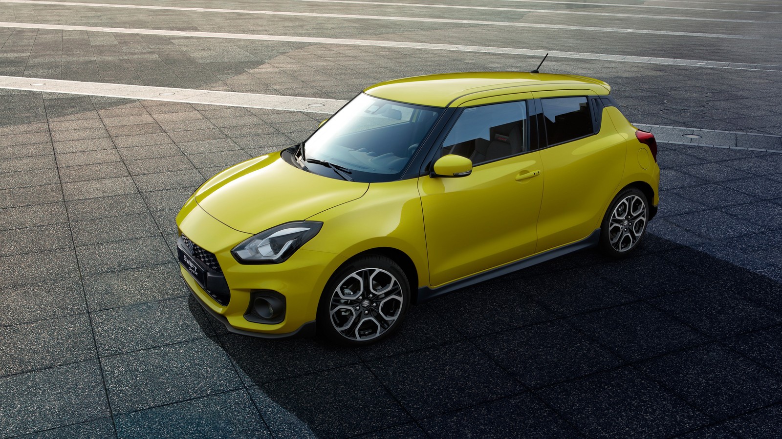 Желтый suzuki swift припаркован на мощеной улице (сузуки, suzuki, машины, спортивный автомобиль, колесо)