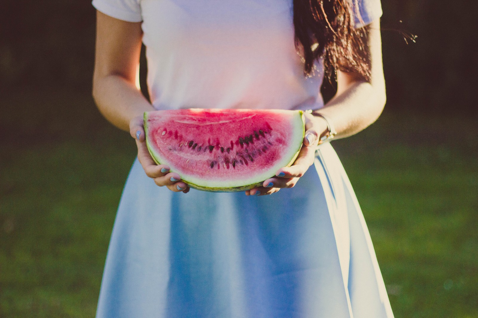 Hay una mujer sosteniendo una rodaja de sandía en sus manos (citrullus, comiendo, vestido, salud, fábrica)