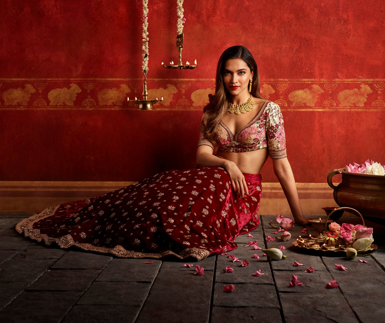 Une femme arabe dans une tenue rouge et dorée assise sur le sol (deepika padukone, traditionnel, actrice indienne, actrice de bollywood, séance photo)