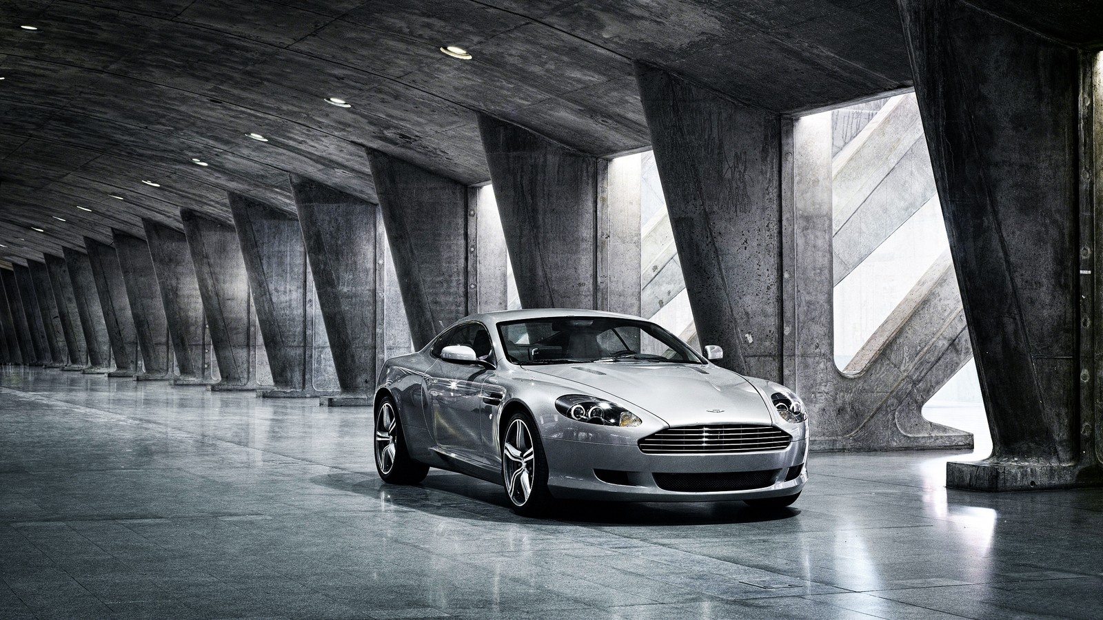 Arafed view of a silver sports car parked in a tunnel (aston martin db9, car, wheel, aston martin dbs, rim)