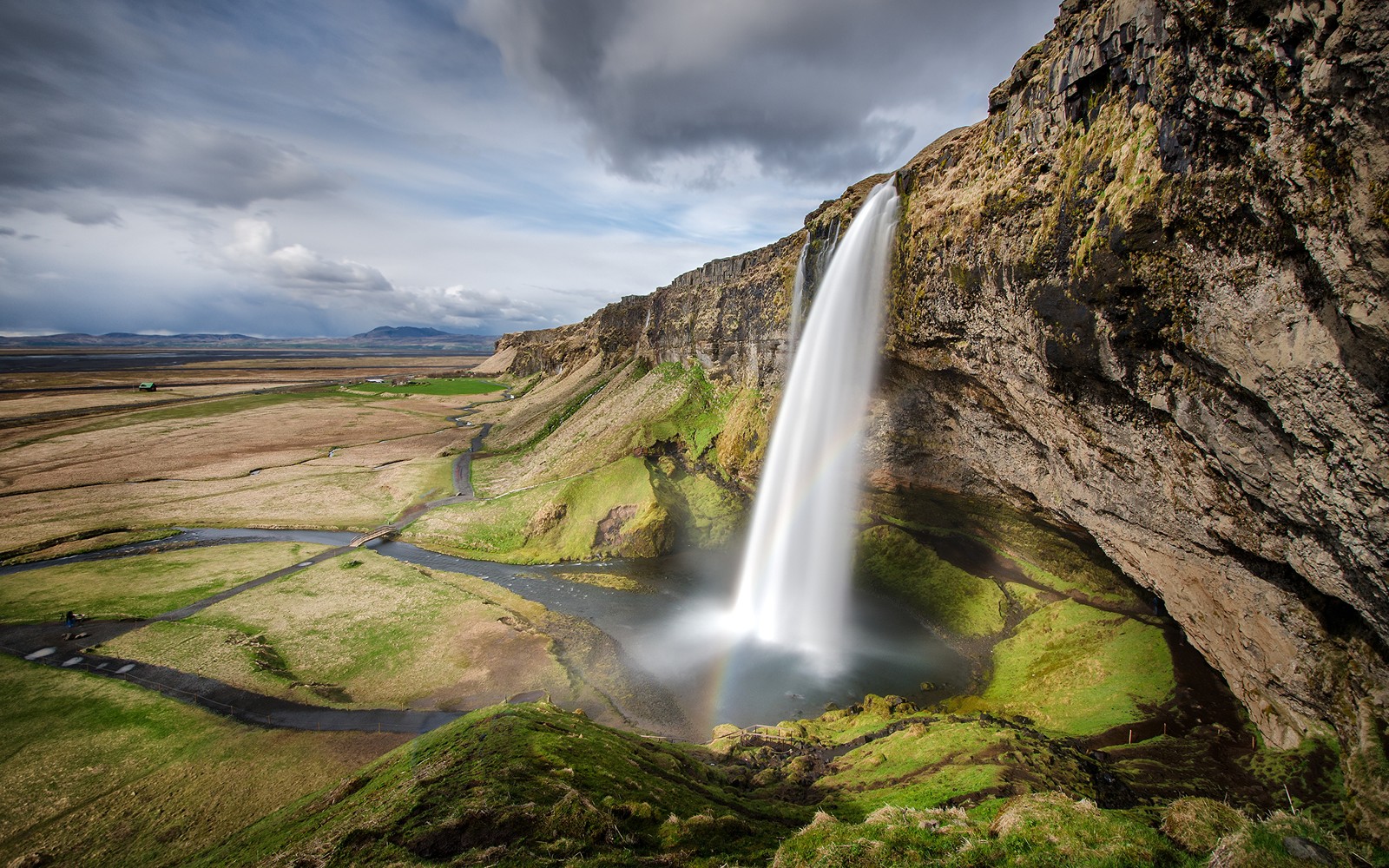 Una cascada en islandia con un arcoíris en el cielo (seljalandsfoss, cascada, cuerpo de agua, naturaleza, agua)