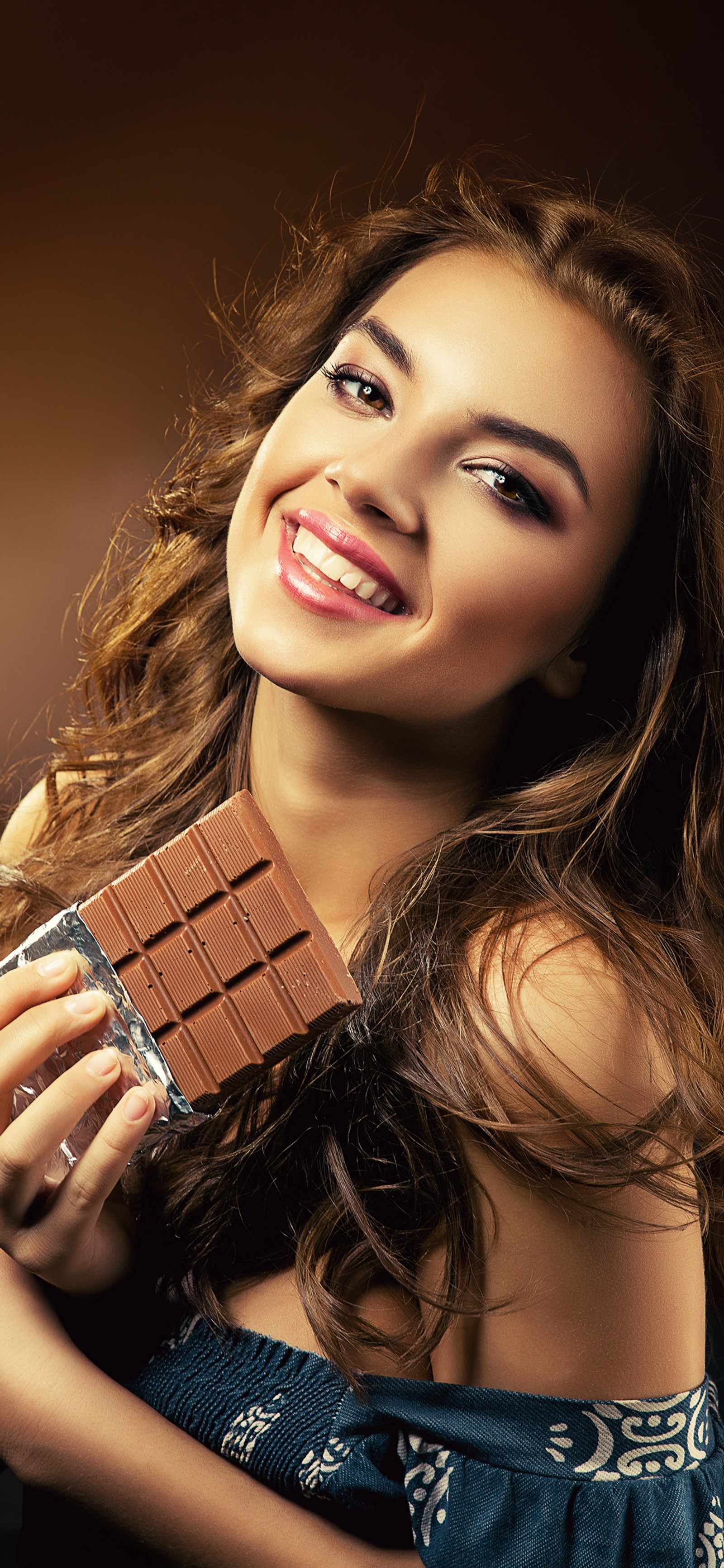 Una jirafa mujer sosteniendo una barra de chocolate y sonriendo a la cámara (belleza, rostro, cabello, piel, cabeza)