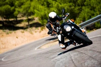 Rider in full gear expertly leaning into a curve on a KTM 990 Super Duke on a winding road.