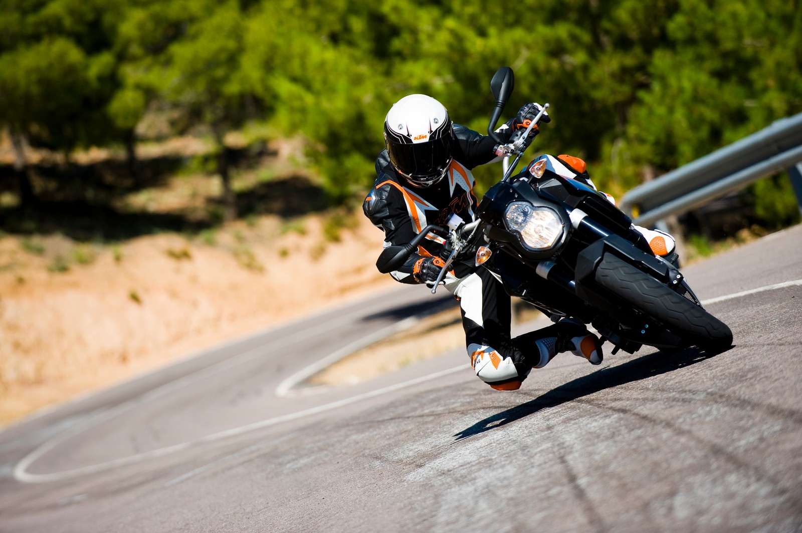 Hay un hombre montando una motocicleta en una carretera sinuosa (supermoto, ktm, coche, motocicleta, ktm 990 super duke)