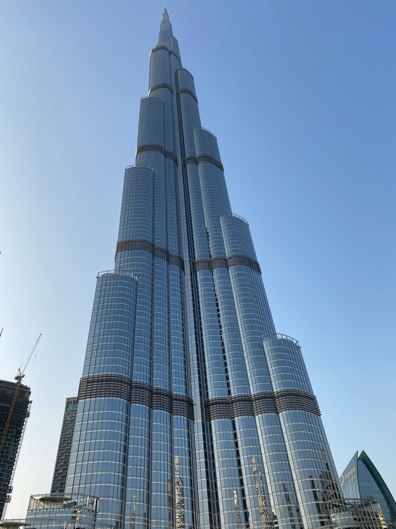 На изображении высокий небоскреб с часами на вершине. (дубай, dubai, burj khalifa, бурдж аль араб, burj al arab)