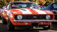 Chevrolet Camaro SS de 1969 em laranja marcante com faixas brancas, exibindo o design clássico de muscle car e a excelência automotiva.