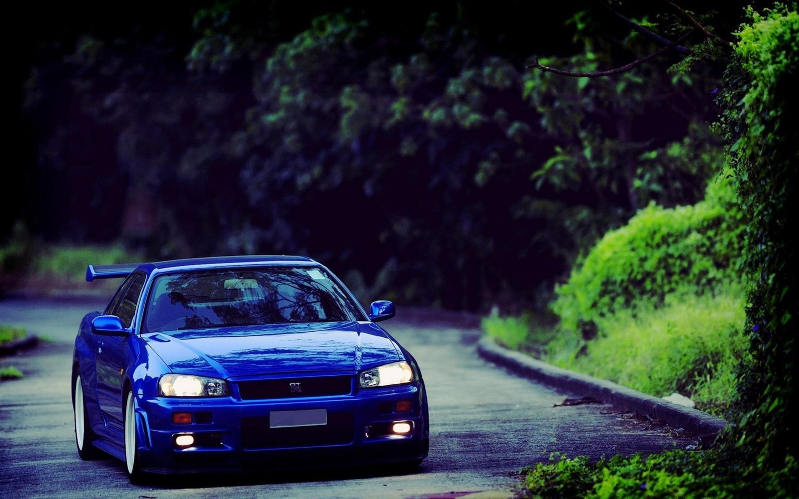 Um carro azul dirigindo por uma estrada com árvores ao fundo (carro, carro esportivo, nissan skyline gt r, nissan skyline gtr, árvore)