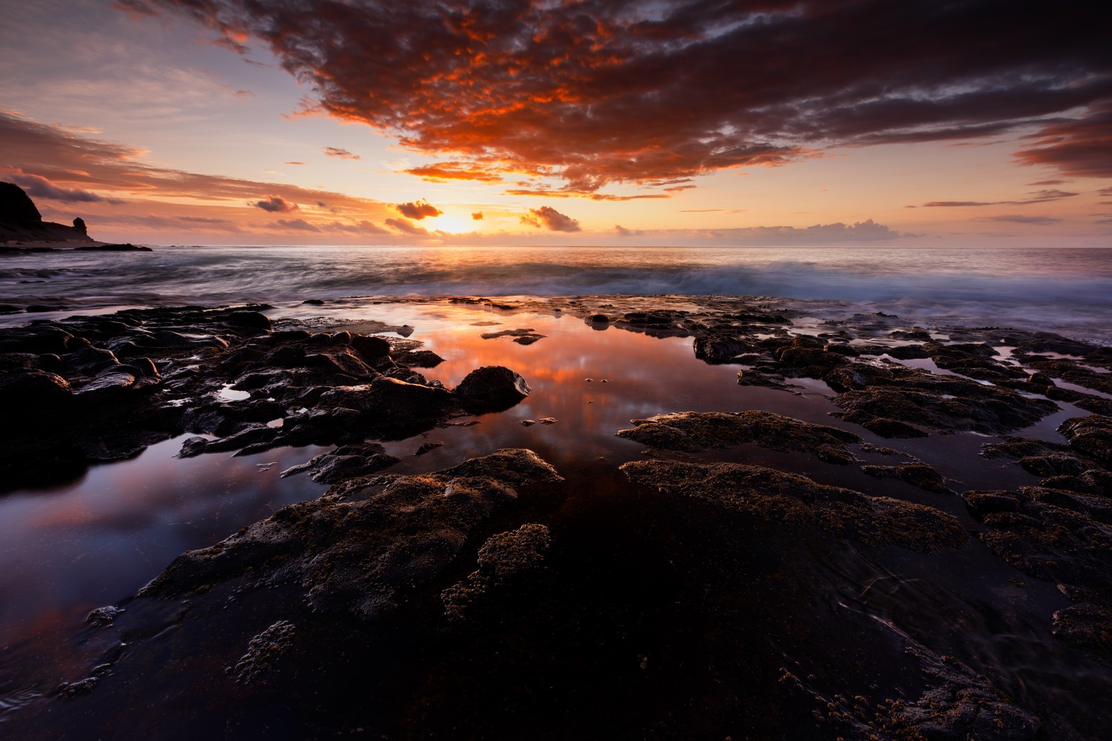 Une vue d'un coucher de soleil sur une plage rocheuse avec un plan d'eau (nuage, eau, atmosphère, ressources en eau, crépuscule)