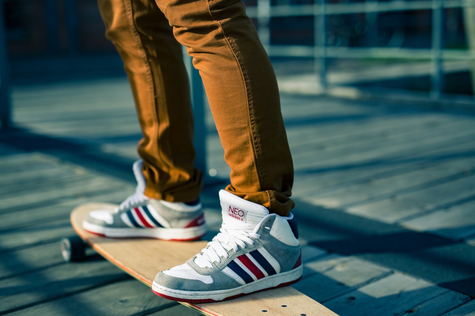 Someone is riding a skateboard on a wooden platform in the sun (shoe, sneakers, skate shoe, clothing, footwear)