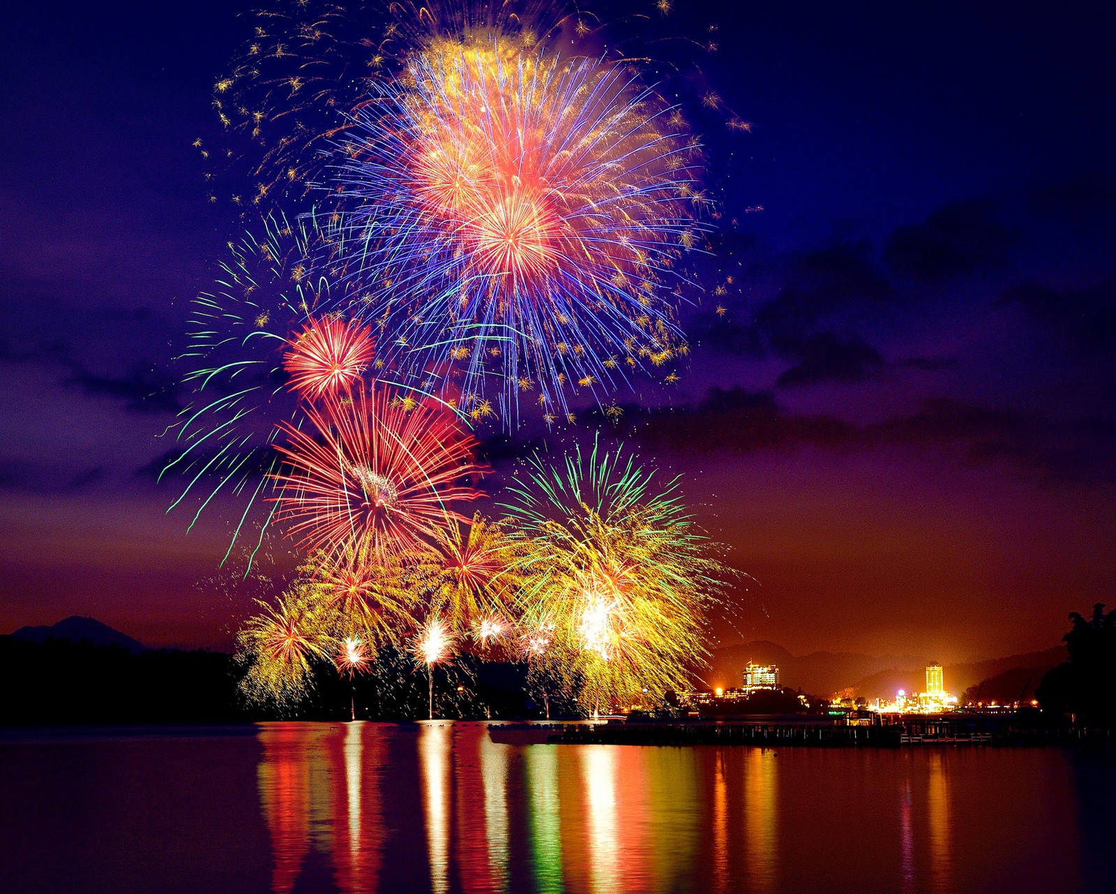 Des feux d'artifice s'illuminent dans le ciel au-dessus d'un lac (célébrer, noël, vacances, lac, lumières)