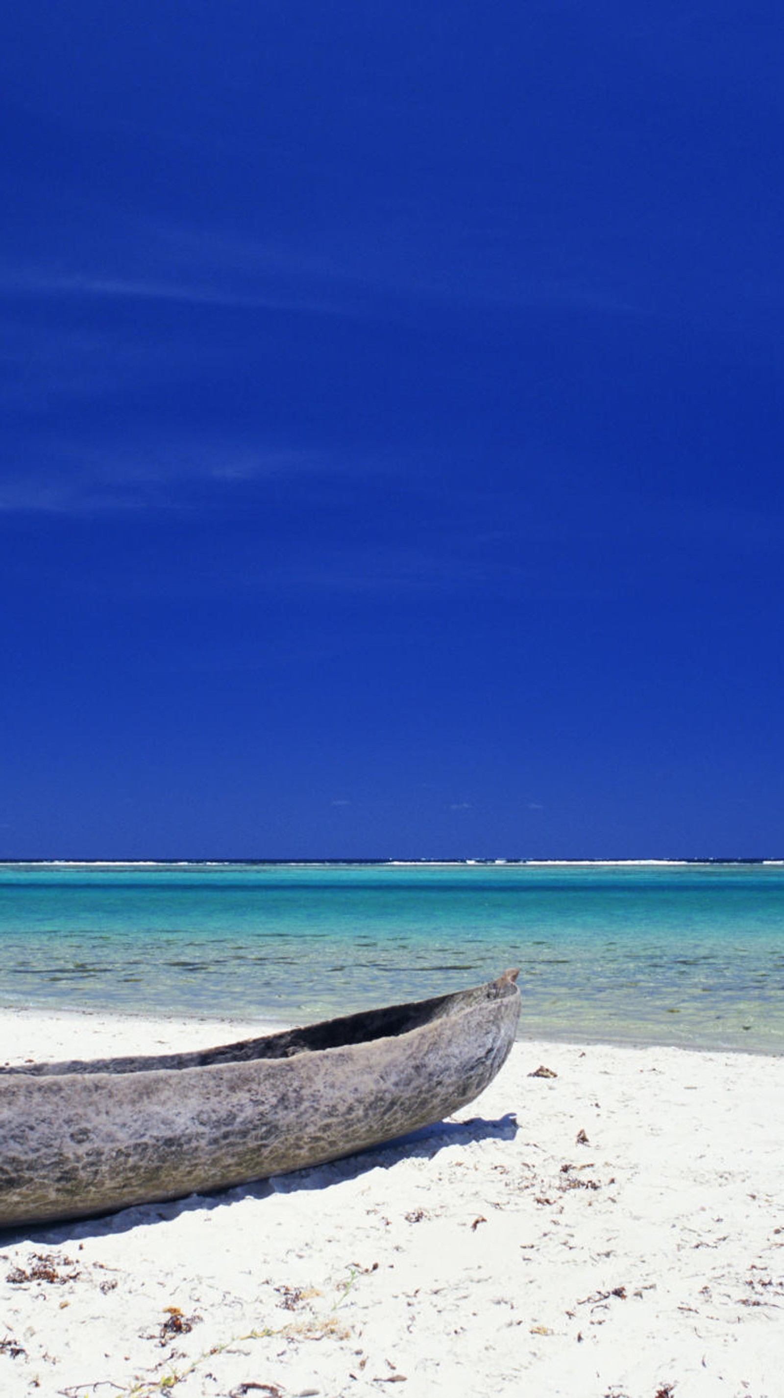 There is a boat on the beach with a blue sky in the background (ocean, summer)