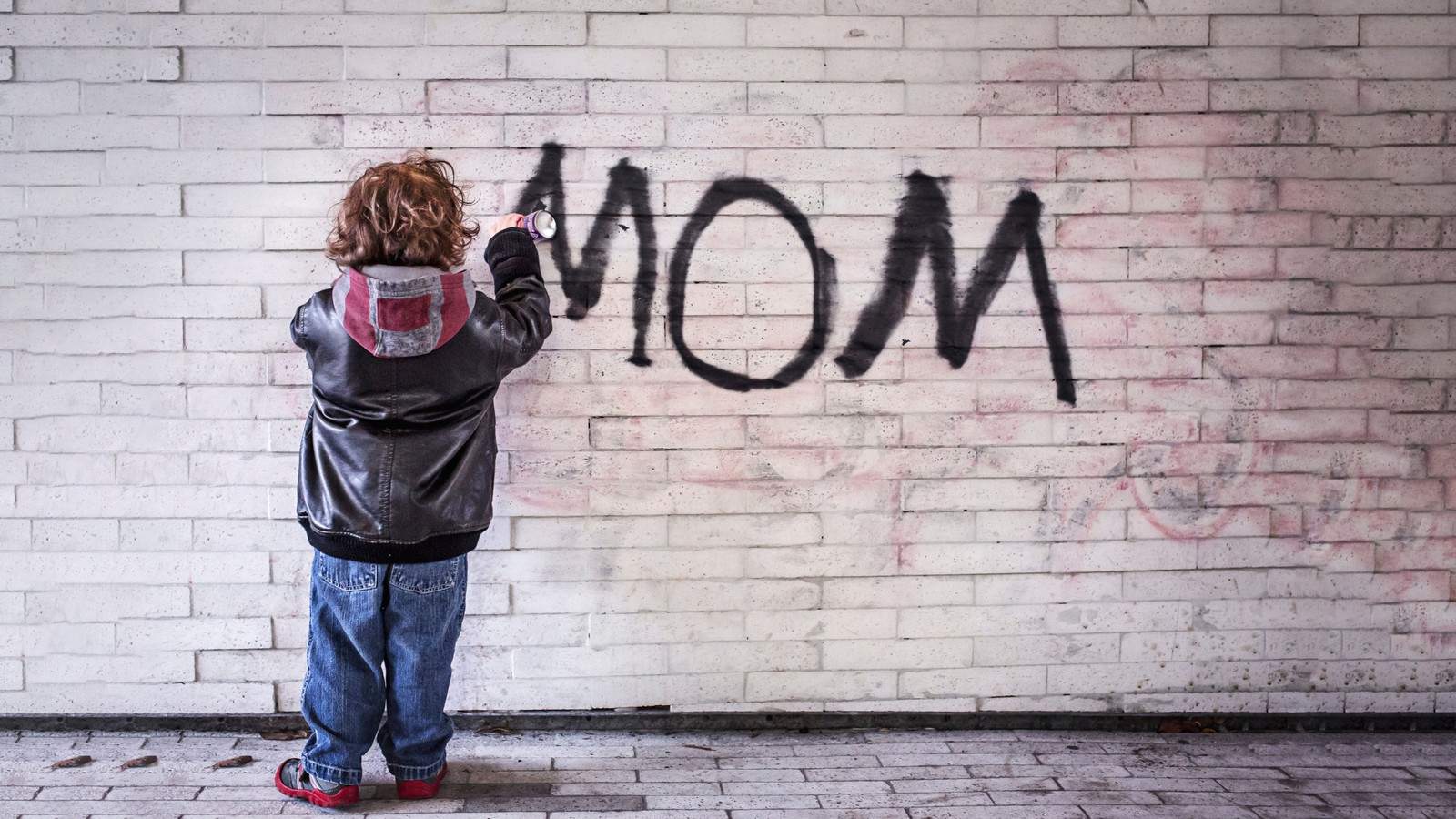 Un enfant arafed écrit le mot maman sur un mur en briques (maman, graffiti, enfant, mur en briques, 5k)