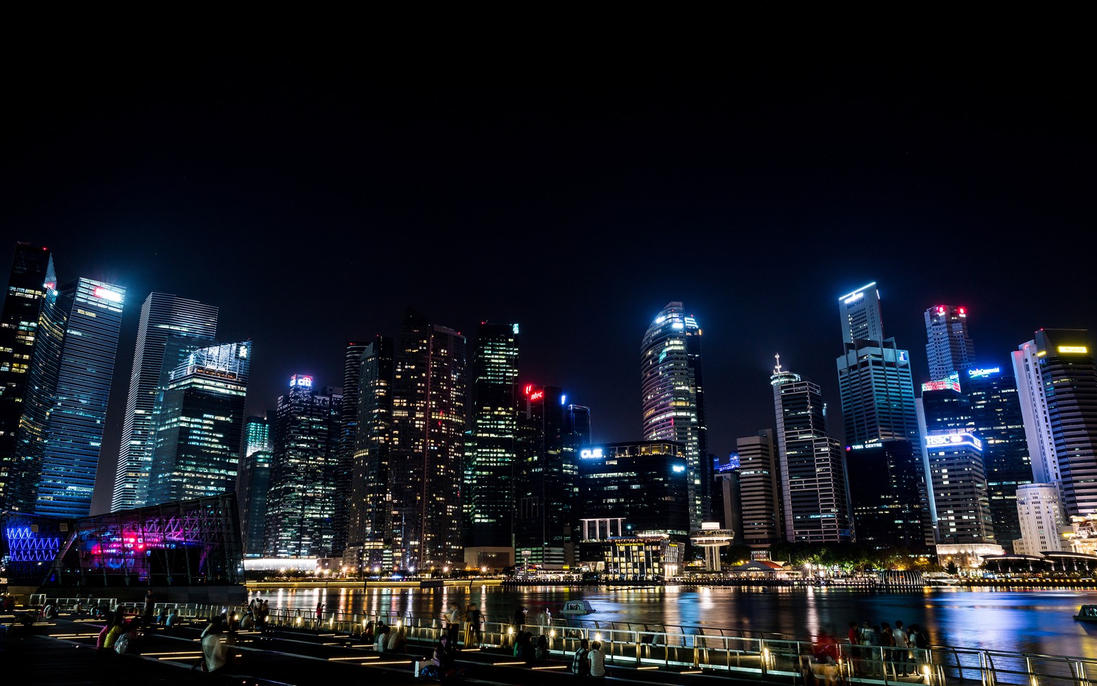 Uma vista impressionante do horizonte da cidade à noite com luzes refletindo na água. (singapura, arranha céus, horizonte, paisagem urbana, metrópole)