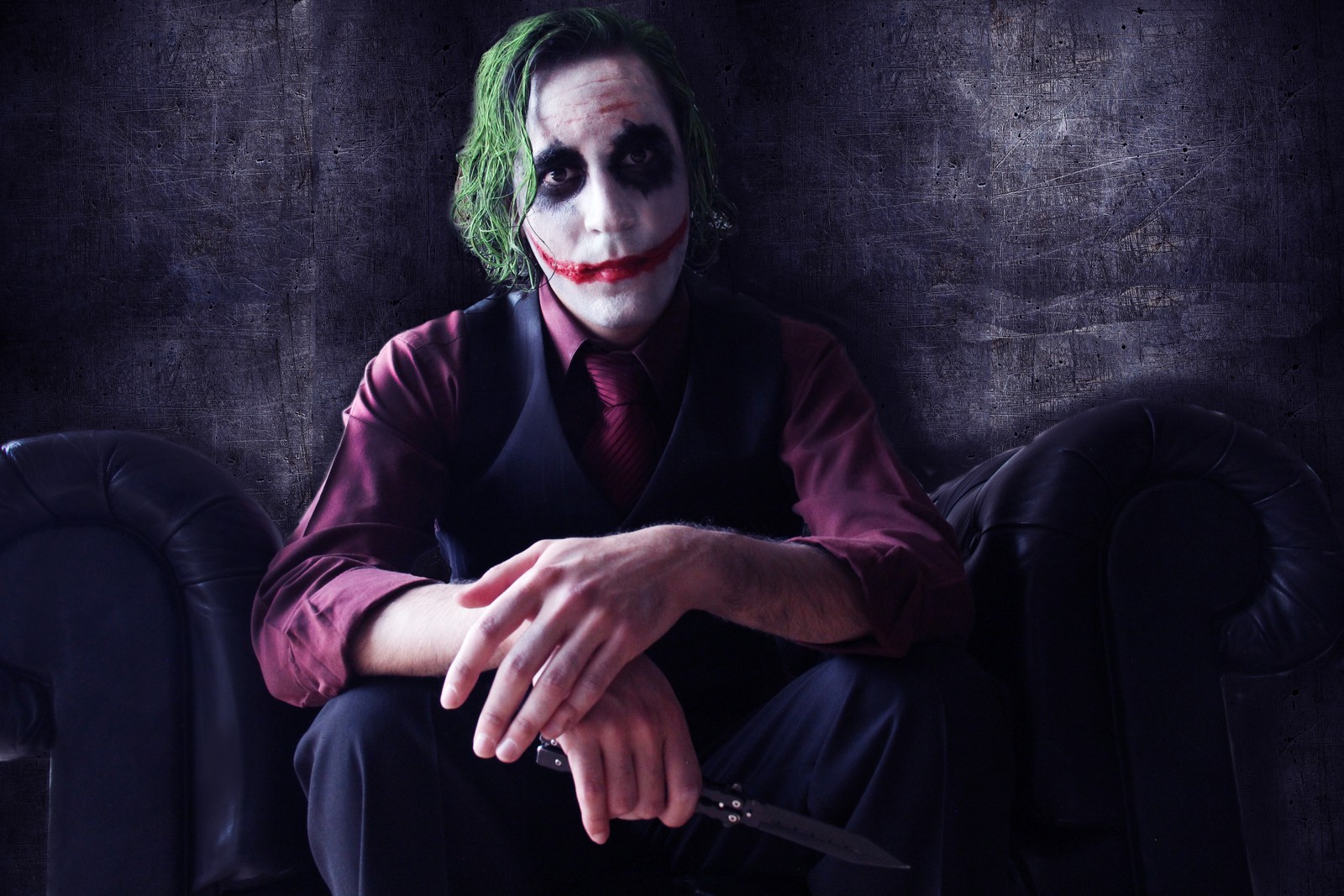 Imagen de un hombre vestido como el joker sentado en un sofá (batman, joker, supervillano, púrpura, oscuridad)