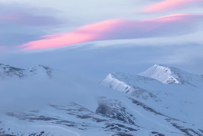 Serene Winter Landscape of Snow-Capped Mountains Under a Soft Pink Sky