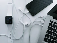 Dispositivos Apple conectados: MacBook, iPhone y reloj inteligente con auriculares y cables