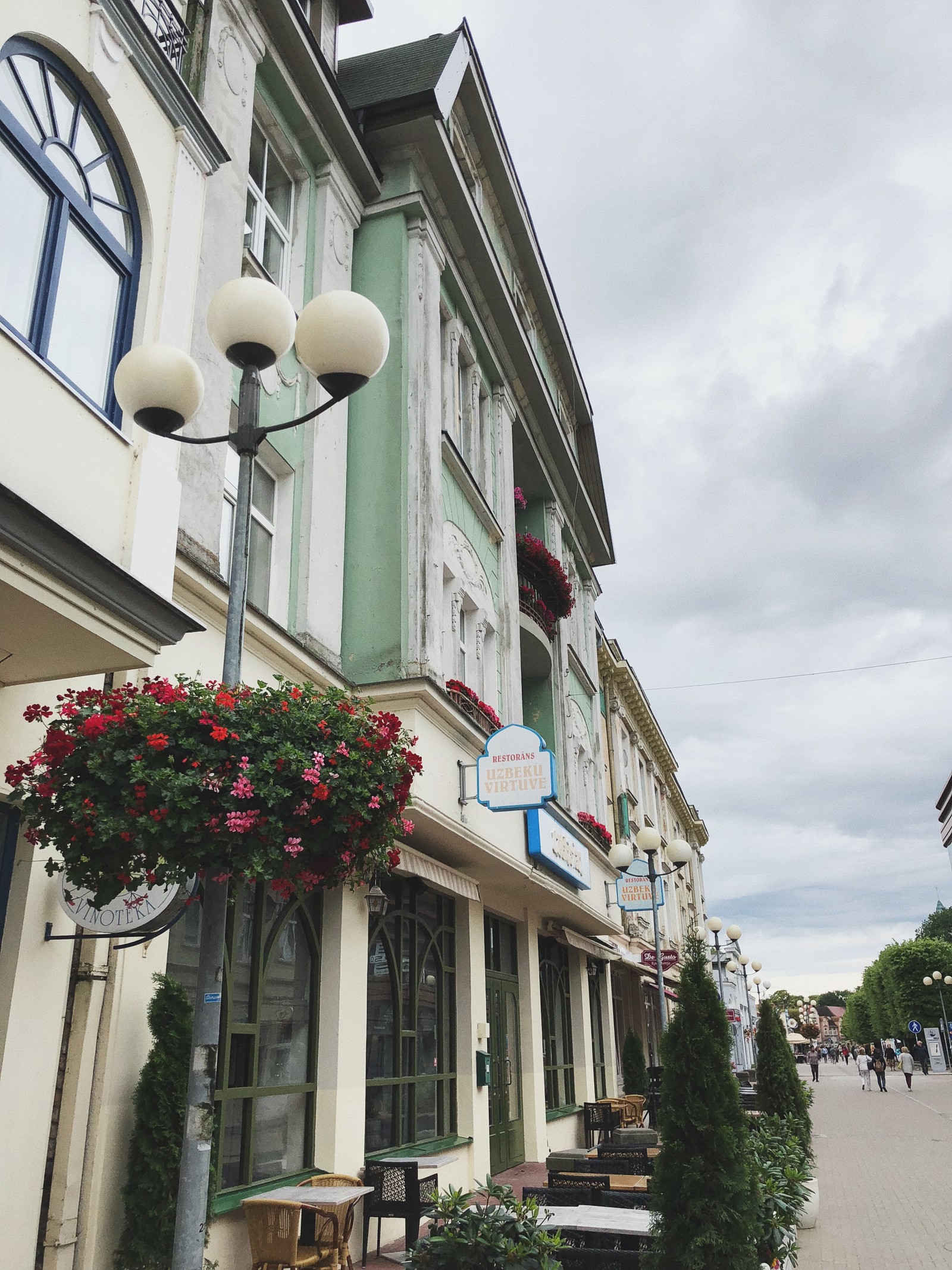 Une rue avec un bâtiment et un lampadaire (maison, immobilier, quartier, ville, pot de fleurs)