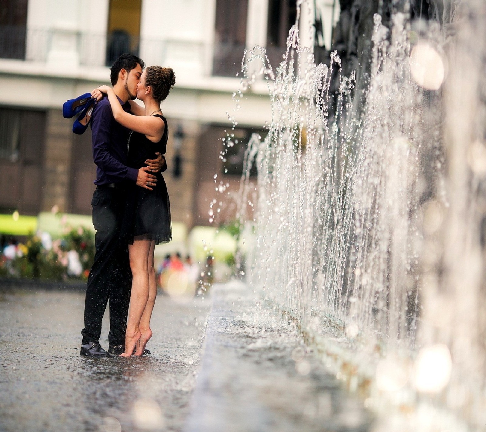 Um homem e uma mulher se beijando em frente a uma fonte (amor)