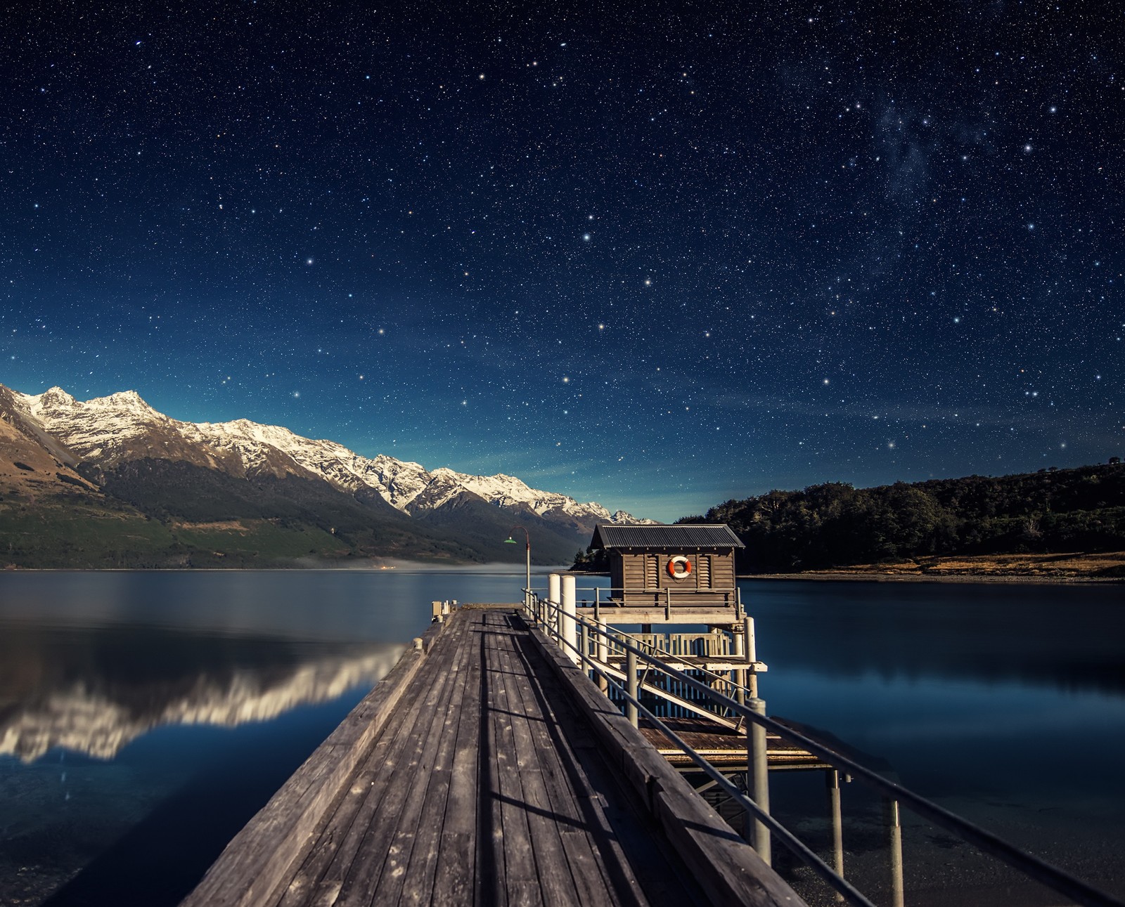 There is a dock with a boat on it and a mountain in the background (lake, nature, night)