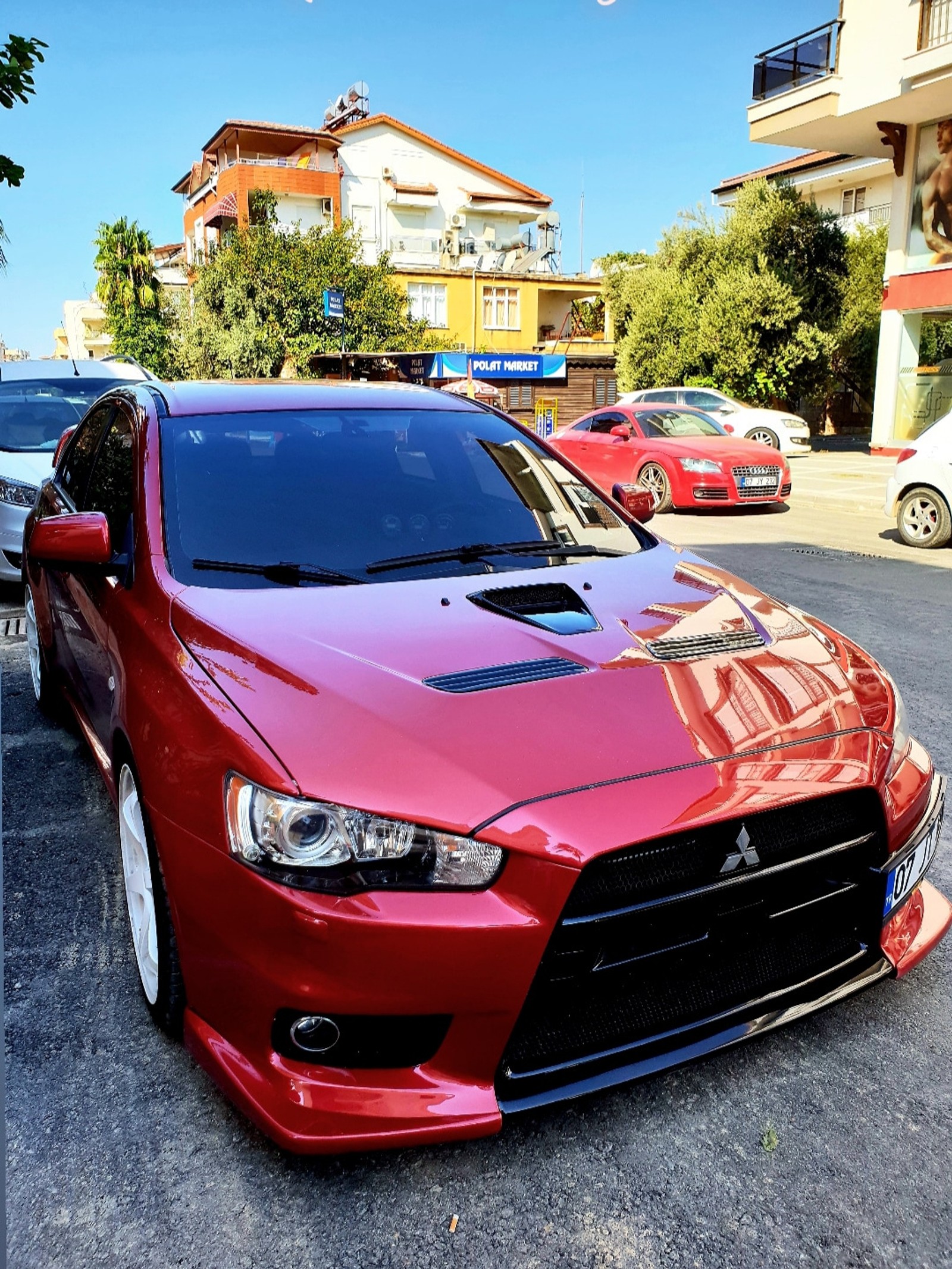 Unscharfes rotes auto, das auf einem parkplatz mit anderen autos parkt (mitsubishi, evox)