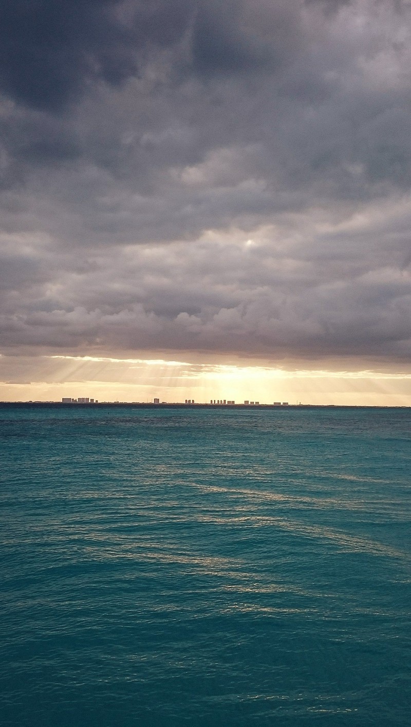 Il y a un bateau sur l'eau sous un ciel nuageux (ville, horizon)