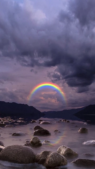 Serene Flusslandschaft mit Regenbogen und Steinreflexionen