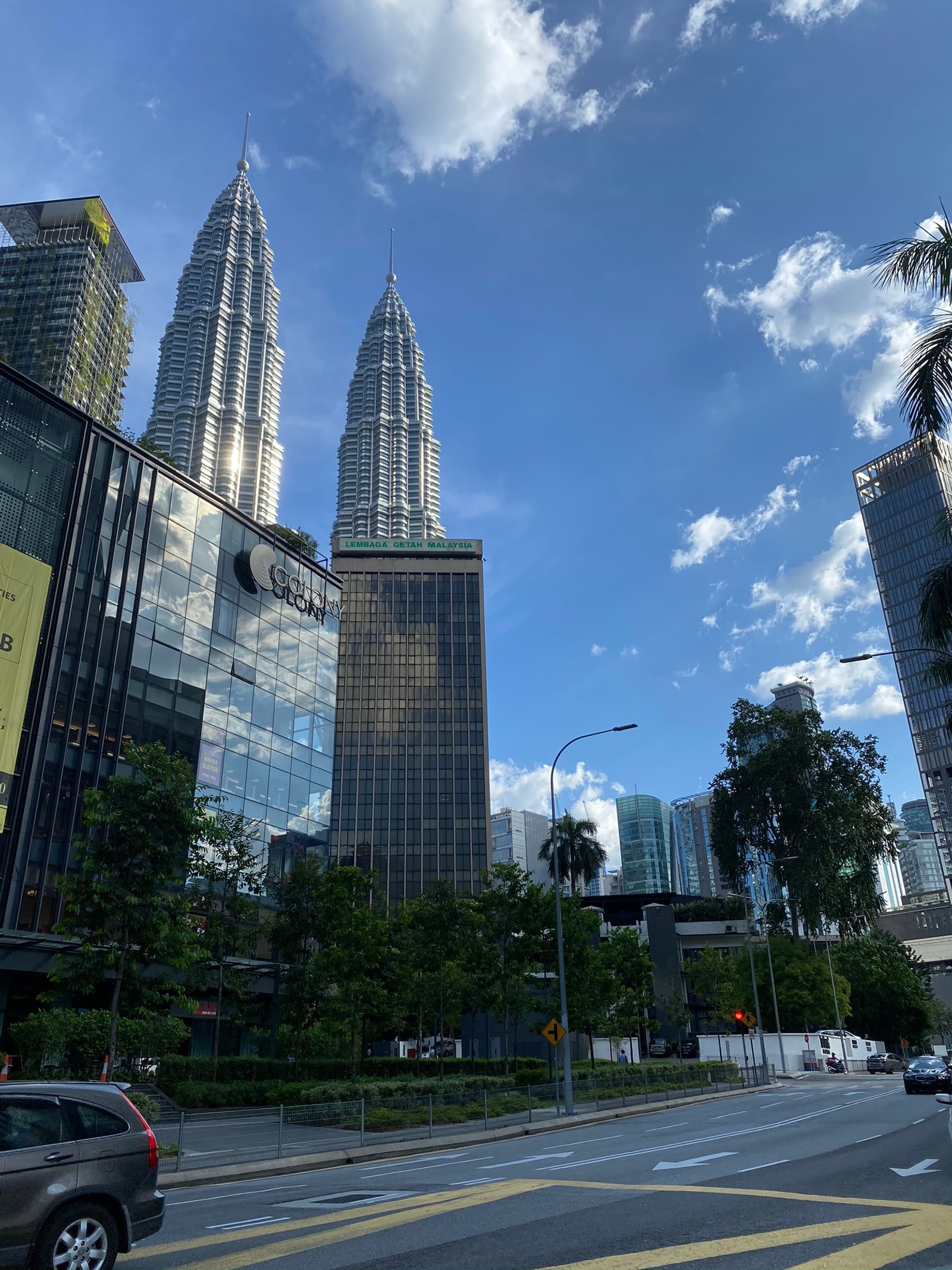 Há muitos edifícios altos na cidade com um fundo de céu (torres petronas, kuala lumpur, dia, estrada, bloco de torre)