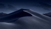 Dunes désertiques sombres sous un ciel étoilé, reflétant le design épuré et l'innovation de la technologie Apple.