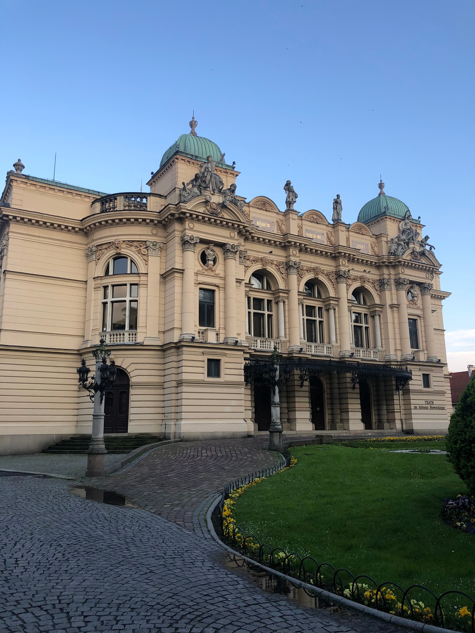 Es gibt ein großes gebäude mit einer uhr auf der vorderseite (theater, architektur, kuppel, fassade, wahrzeichen)