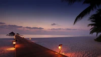 Serene beach pier at sunset, leading into a tranquil sea under a vibrant sky.