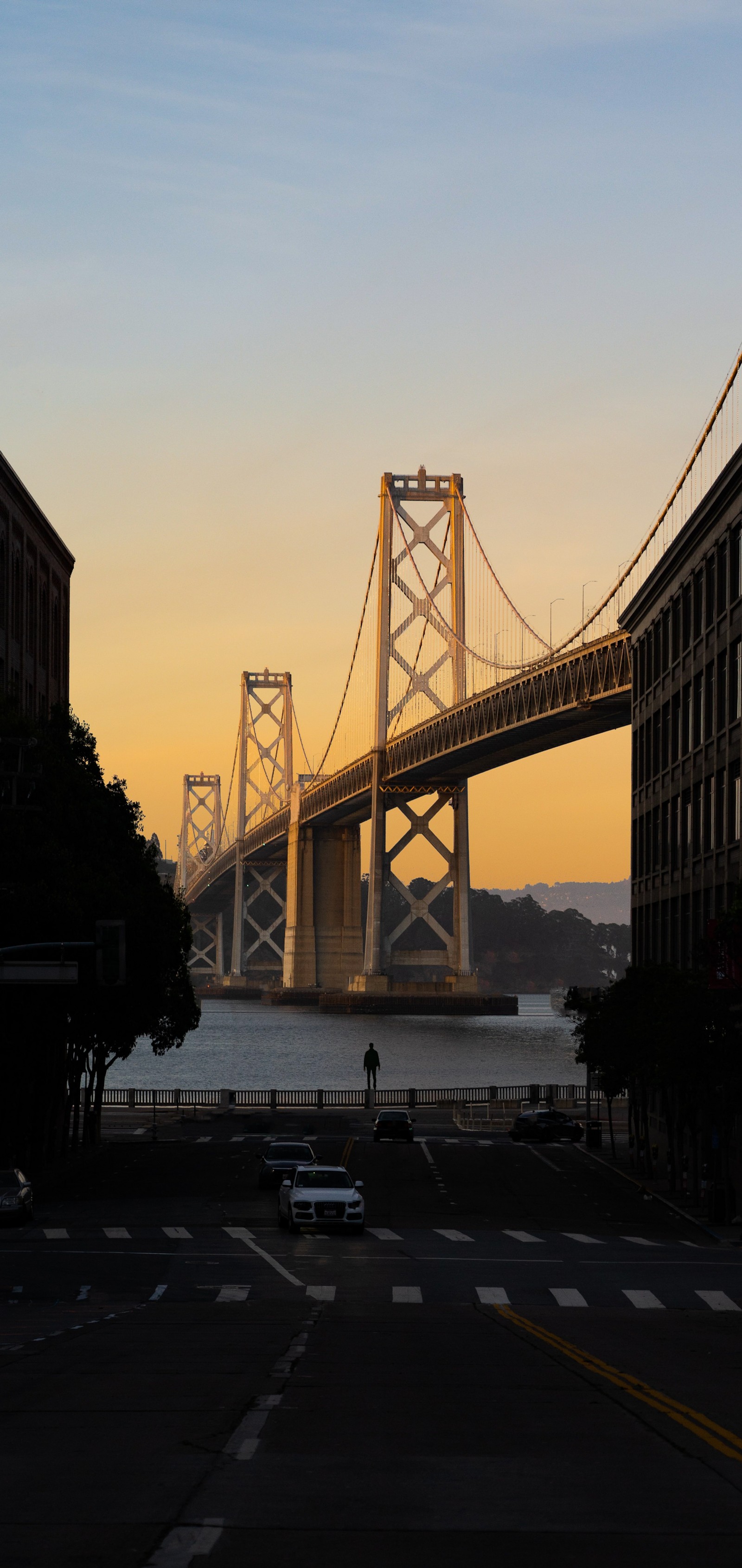 Vista arafed de uma ponte sobre uma rua da cidade ao pôr do sol (nuvem, infraestrutura, carros, árvore, água)