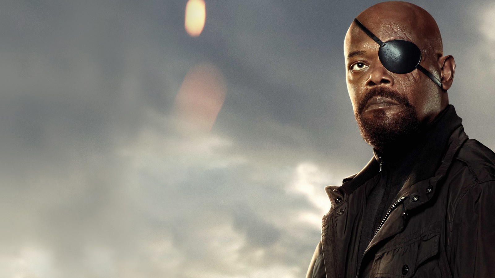 Un hombre con un parche negro en el ojo de pie frente a un cielo nublado (nick fury, spider man lejos de casa, spider man far from home, película, samuel l jackson)