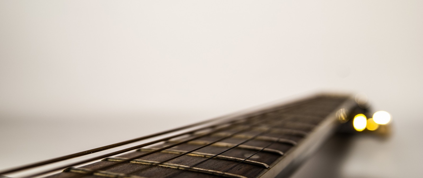 There is a close up of a guitar neck with a yellow light (close up, guitar, design, vulture)