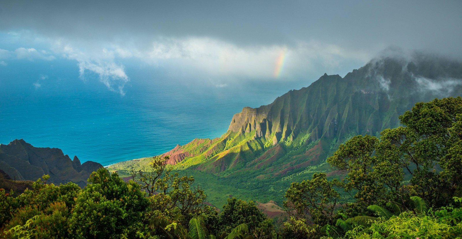 Une vue d'un arc-en-ciel au-dessus d'une montagne avec un arc-en-ciel dans le ciel (vallée de kalalau, formes montagneuses, montagne, nature, paysage naturel)