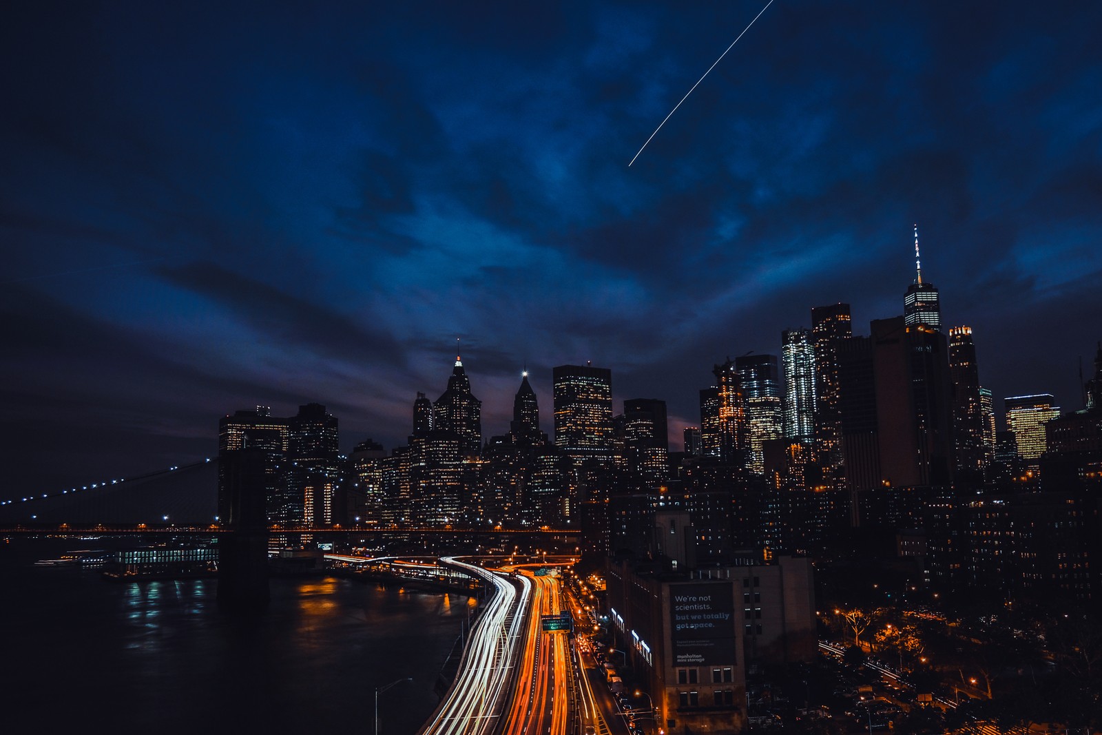 Uma vista do horizonte da cidade à noite com um jato voando acima (noite, paisagem urbana, cidade, área urbana, linha do horizonte)