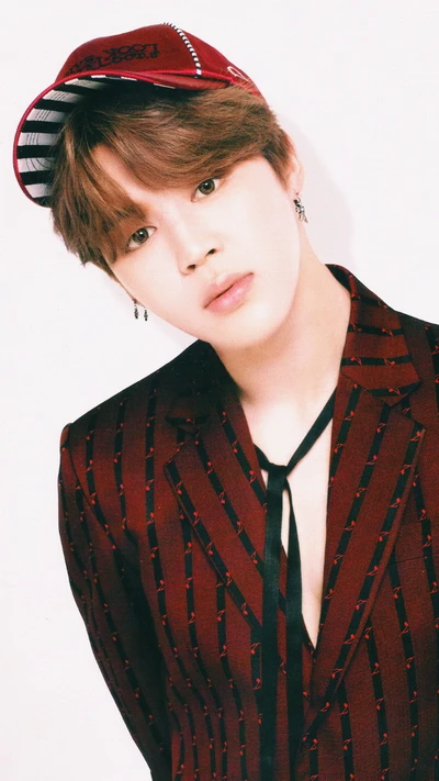 Jimin de BTS en un elegante traje a rayas y gorra, exudando carisma y encanto.