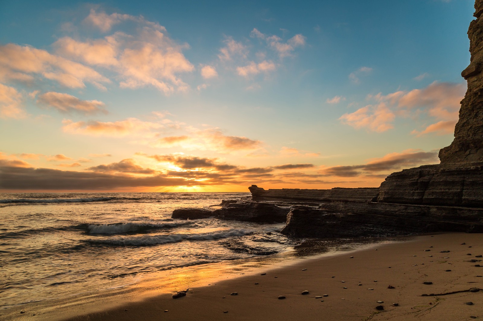 Coucher de soleil sur une plage avec une formation rocheuse et un chien sur le rivage (mer, nuage, eau, atmosphère, paysage naturel)