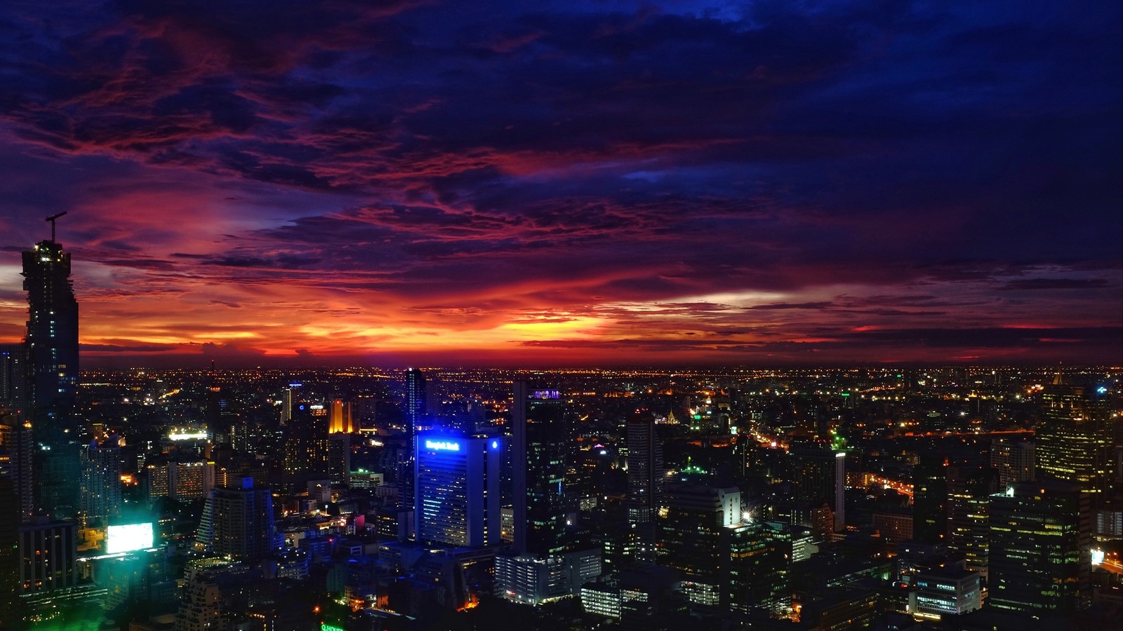 Uma vista de uma cidade à noite com um céu colorido. (bangkok, por do sol, cidade, paisagem urbana, área urbana)