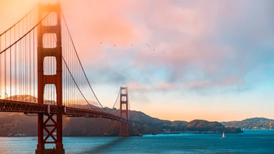 Die Golden Gate Bridge in der Dämmerung, eingerahmt von einem ruhigen blauen Himmel und sanften Wolken, die einen warmen Nachglanz über das Wasser werfen.