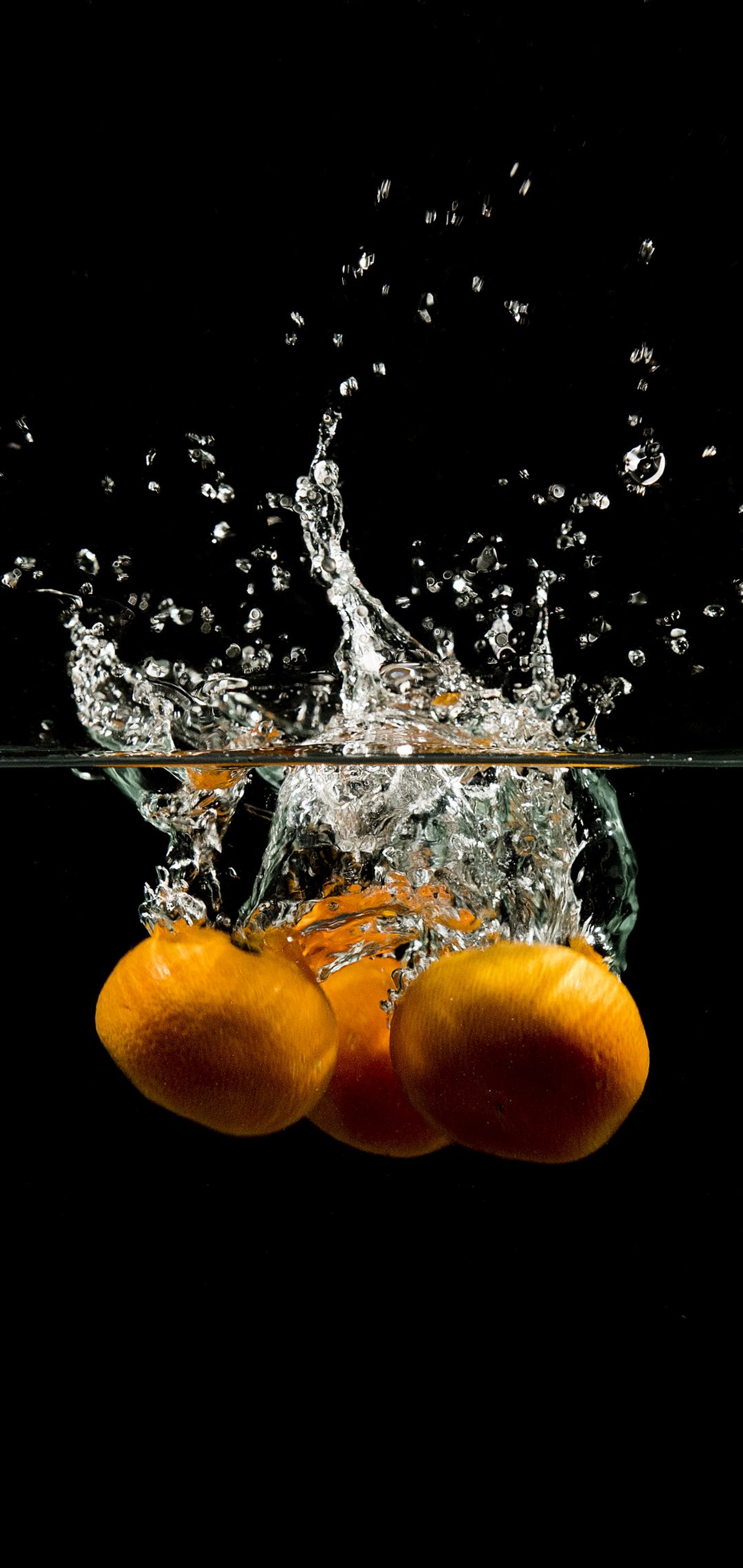 Hay una naranja cayendo al agua con un salpicón de agua (agua, planta, líquido, comida, fluido)