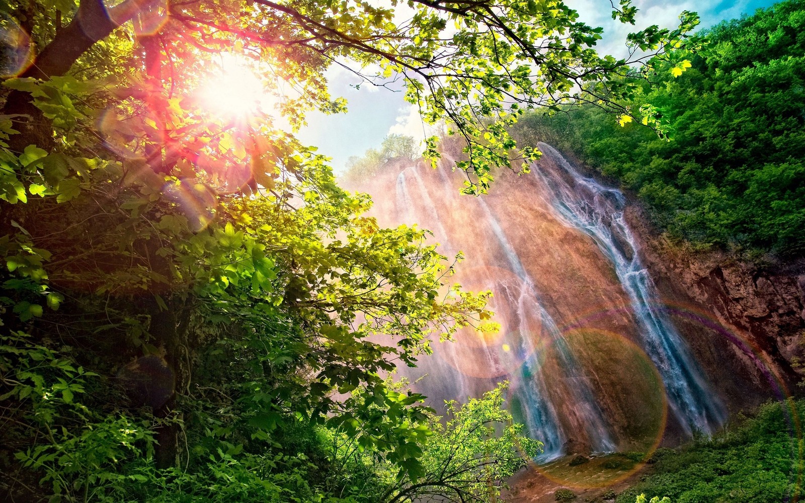 Blick auf einen wasserfall im dschungel mit sonnenstrahlen, die durch die bäume scheinen (wasserfall, natürliche landschaft, natur, vegetation, wasser)