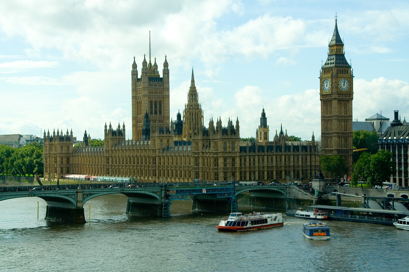 Jirafas en el agua frente a un gran edificio con un reloj (casas del parlamento, big ben, palacio de westminster, hito, rio)