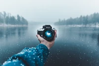 Nikon-Kamera, die eine Winterlandschaft in der Hand über Wasser reflektiert