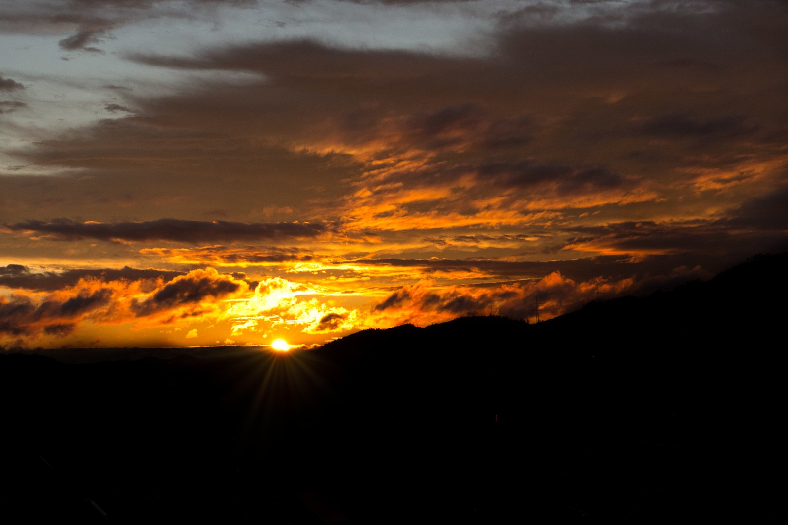 A view of a sunset with a few clouds and a person on a surfboard (sunset, cloud, atmosphere, ecoregion, amber)